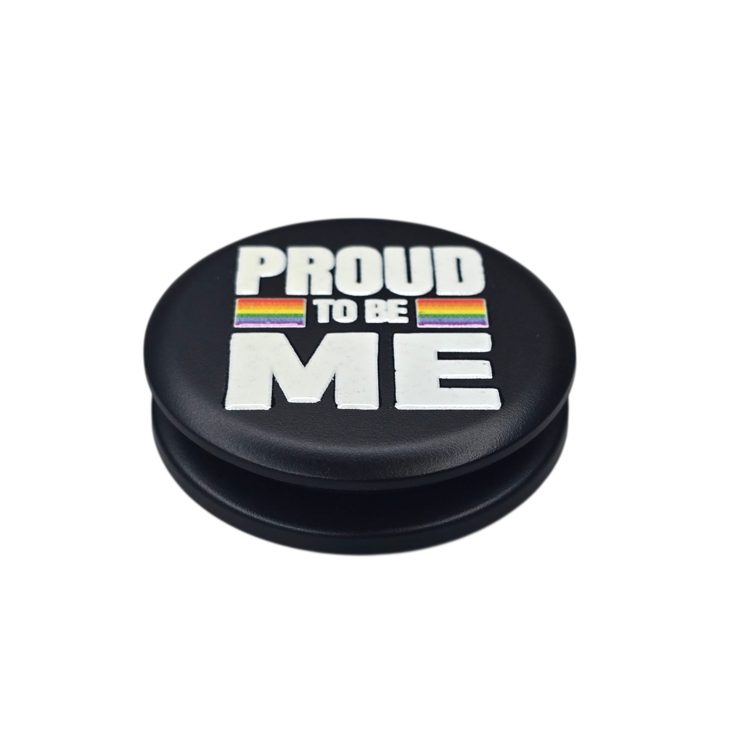 Sateenkaaren väreillä koristeltu musta puhelinpidike, jossa teksti "Proud to be me"